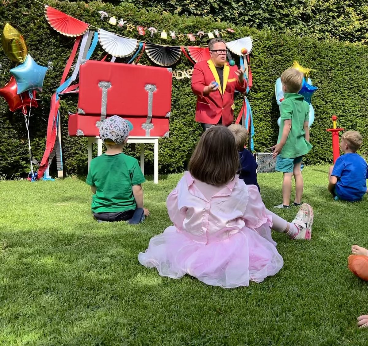 Kinder sitzen auf bunten Sitzkissen und schauen der Zaubershow zu